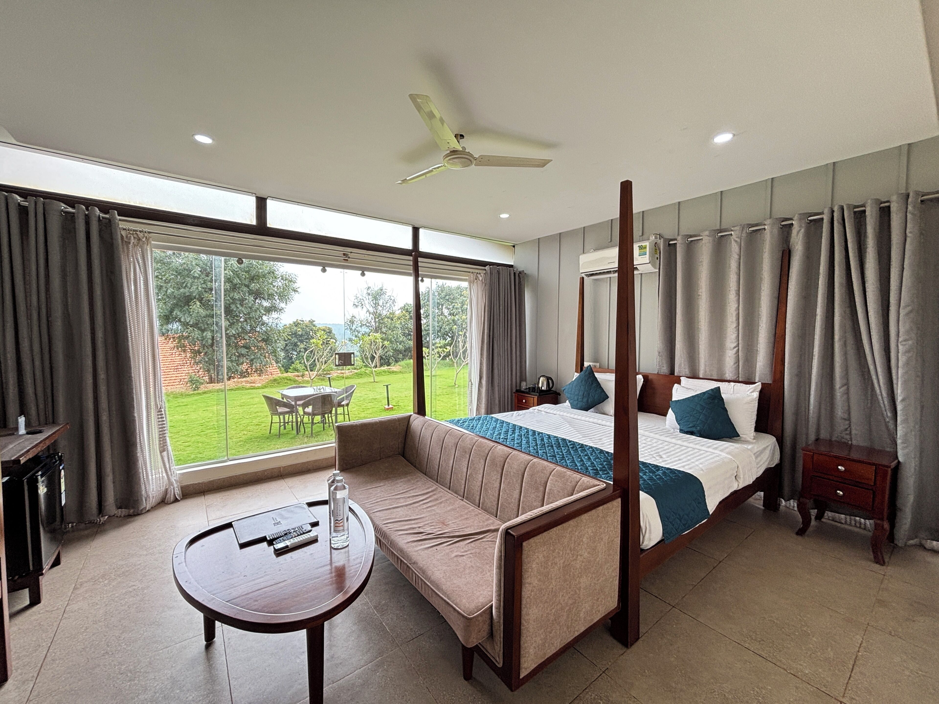 Un dormitorio con cama con dosel, una zona de estar con una mesa y vistas al exterior.