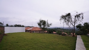 A grassy yard with a house and a stone pathway. - Ravishing Retreat  (Ramanagara)