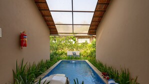 A swimming pool with a glass ceiling, surrounded by plants, and a fire extinguisher on the wall. - Ravishing Retreat  (Ramanagara)
