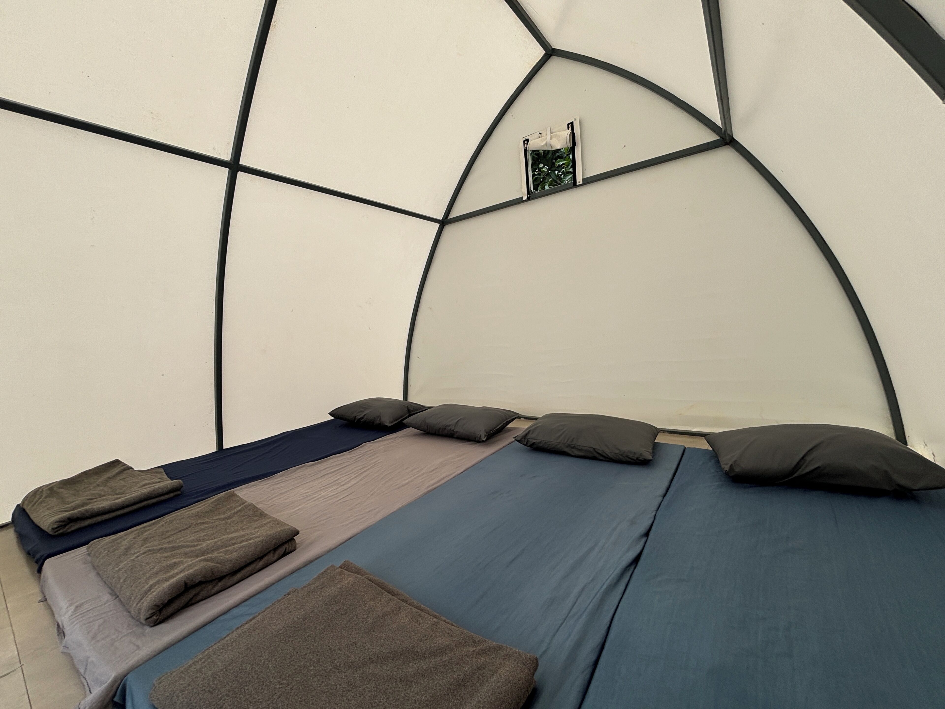 A room with a bed, pillows, and a small window.