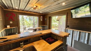 Ein Restaurantinneres mit einer Holztheke, einer Sitzgelegenheit und Blick ins Freie.