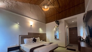 A modern bedroom with a large bed, a wooden ceiling, and a small desk area. - Chill Berg Resort - Bodimettu (Bodinayakanur)