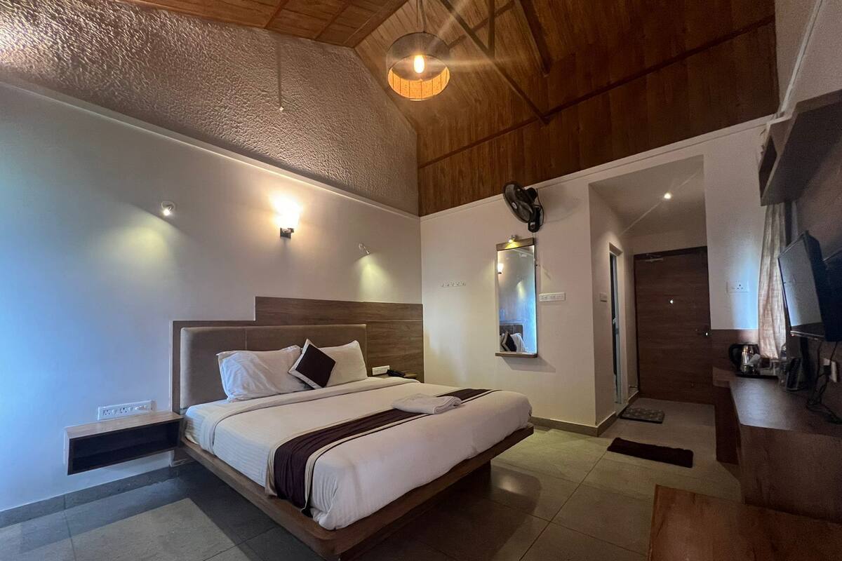 A modern bedroom with a large bed, a wooden ceiling, and a small desk area.