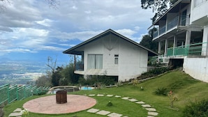 A modern house with a circular patio, a small garden, and a view of a valley. - Chill Berg Resort - Bodimettu (Bodinayakanur)