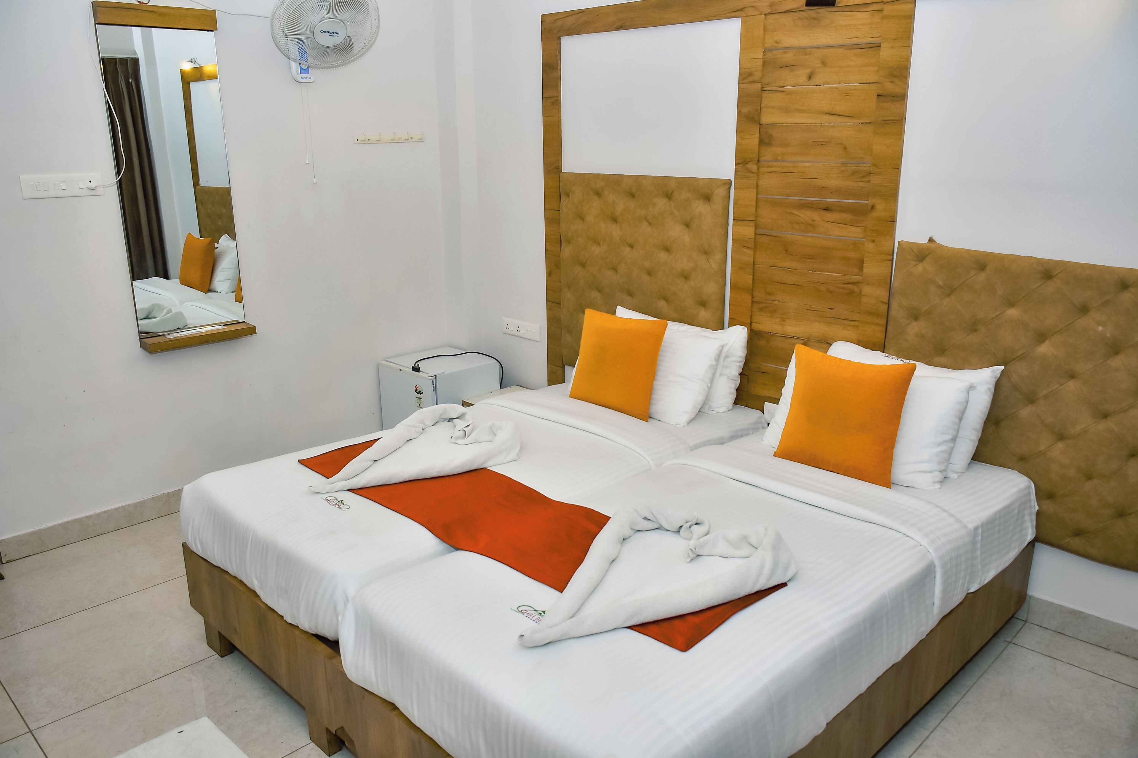 Una habitación de hotel con una cama grande, un cabecero de madera, un espejo y una mesita de noche.