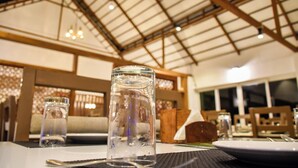 A dining area with a high ceiling, wooden beams, and tables set for dining. - Chill Berg Resort - Bodimettu (Bodinayakanur)