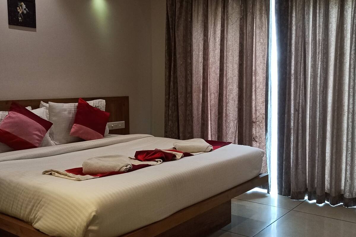 A neatly made bed with white and red bedding, a wooden headboard, and a picture on the wall.