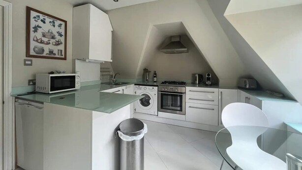 A modern kitchen with a microwave, washing machine, oven, and a sink. - Modern Top Floor 2BD Flat - Kensington (London)