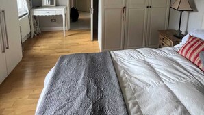 A bedroom with a bed, a desk, and a wardrobe. - Modern Top Floor 2BD Flat - Kensington (London)