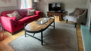 A living room with a red sofa, a wooden coffee table, a TV, and a lamp. - Modern Top Floor 2BD Flat - Kensington (London)