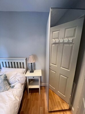 A bedroom with a bed, bedside table, lamp, and a wardrobe.