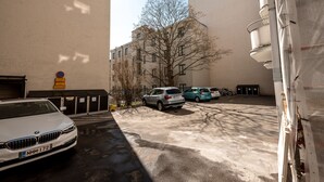 A parking area with a white car, a tree, and a building with a sign. - 2ndhomes Cozy Apartment with Park View (Helsinki)