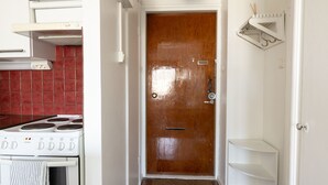 A kitchen with a white stove, a wooden door, and a red tiled backsplash. - 2ndhomes Cozy Apartment with Park View (Helsinki)