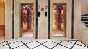 An elevator with two doors, marble walls, and a tiled floor. - Hotel Vanson Delite (New Delhi)