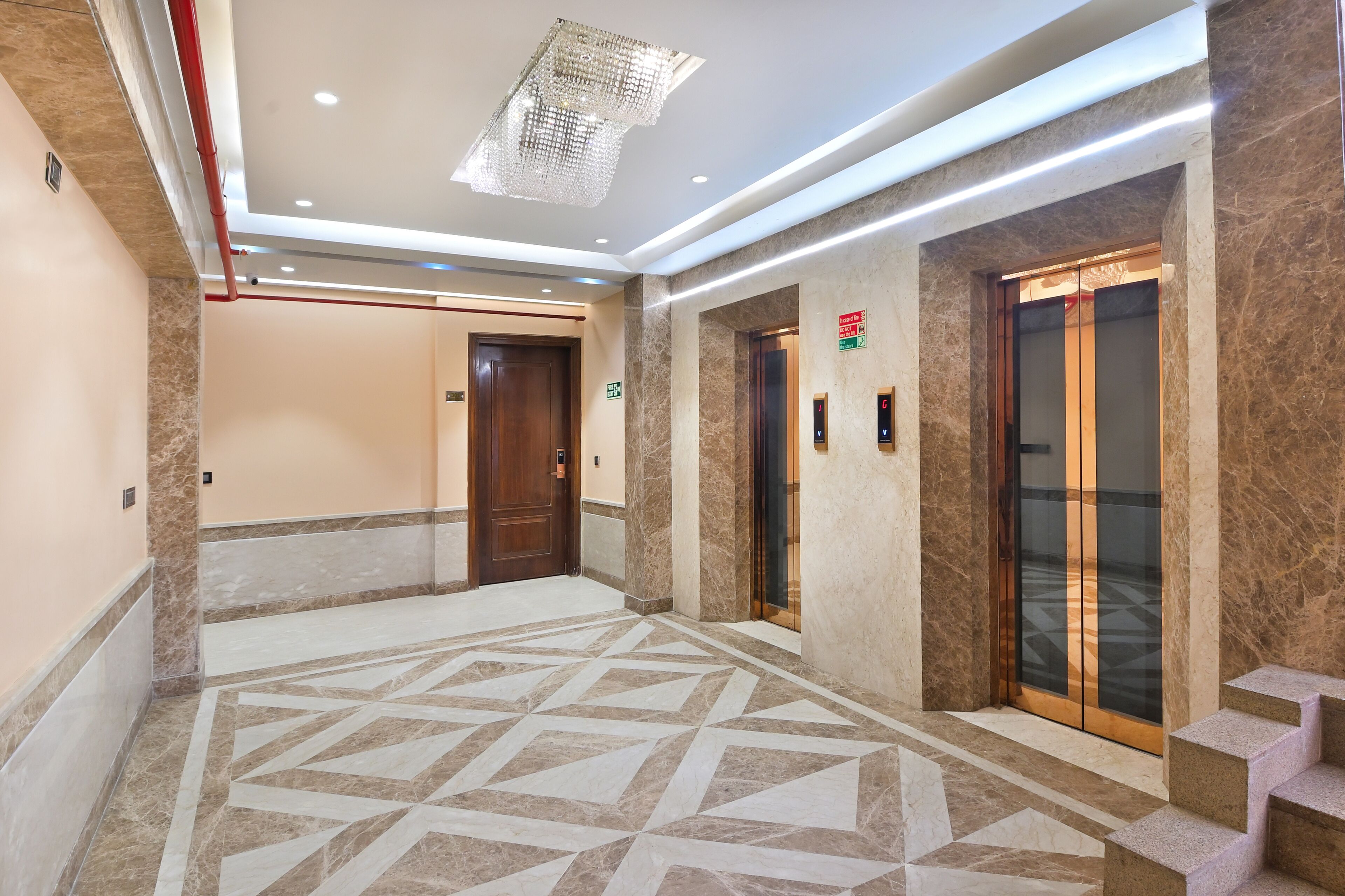 A modern hotel lobby with marble flooring, wooden doors, and elevators.