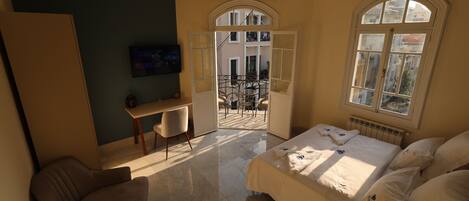 Une chambre d’hôtel avec un lit, un bureau, une chaise et une vue sur le balcon extérieur.