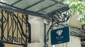 Señal del 'The Gem Boutique Hotel' con una barandilla de metal decorativa y una lámpara colgante.