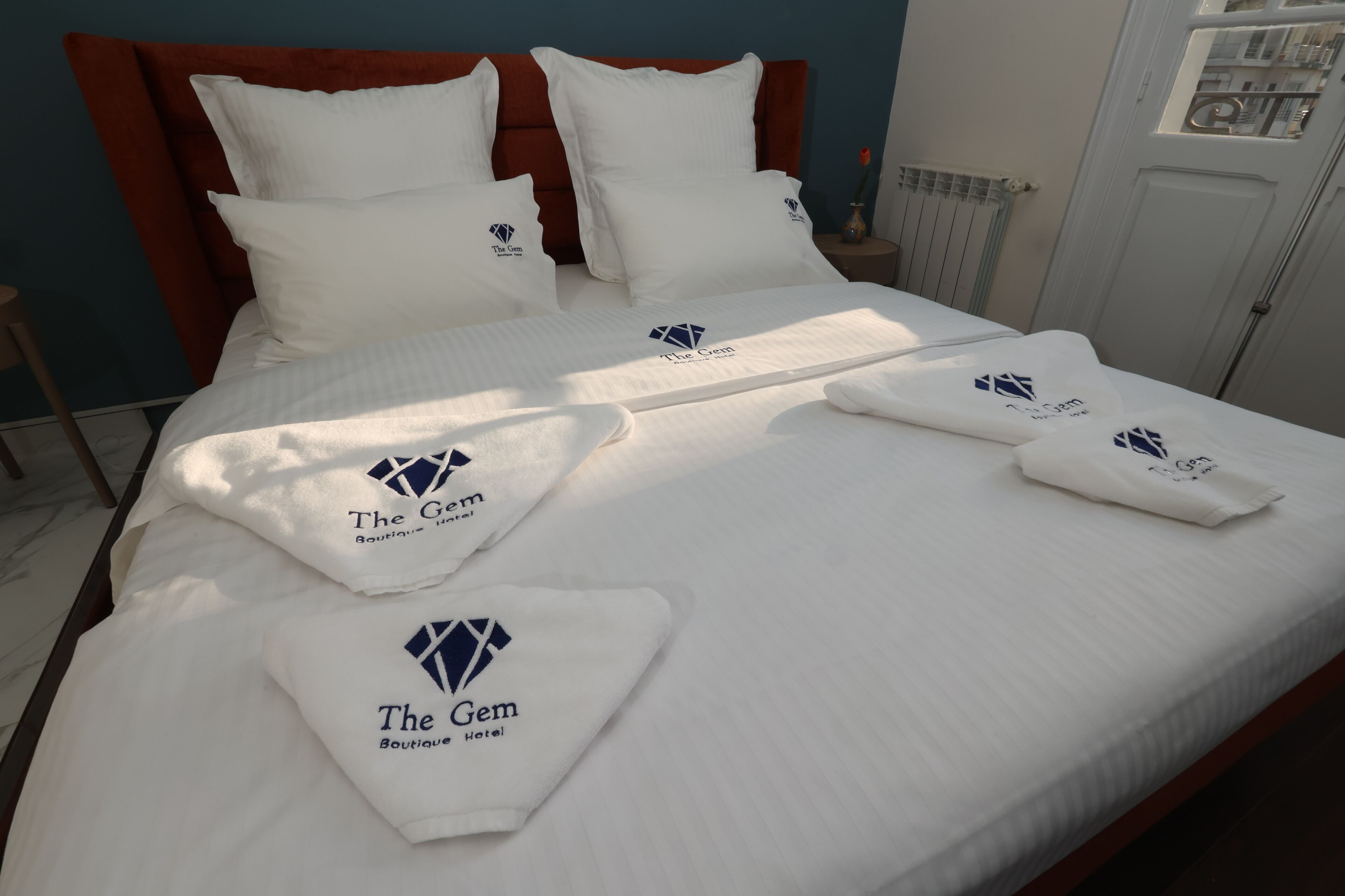 Una habitación de hotel con una cama bien hecha, ropa de cama blanca y un cabecero rojo.