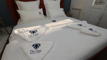 Una habitación de hotel con una cama bien hecha, ropa de cama blanca y un cabecero rojo.
