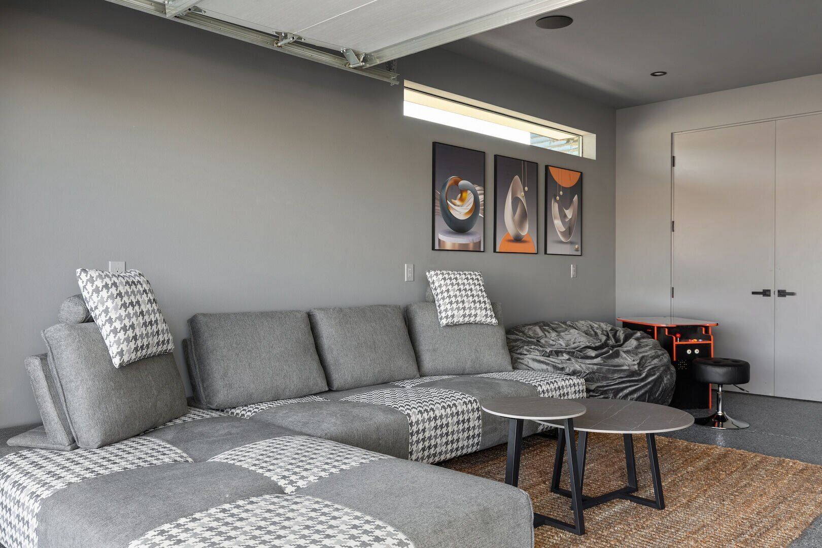 Una sala moderna con un sofá seccional gris, una mesita redonda y un plaid estampado de galgo.