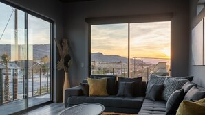 Una sala de estar moderna con un ventanal grande, un sofá gris oscuro y una mesa de centro redonda.