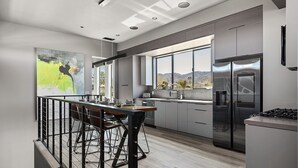 Una cocina moderna con una isla central, electrodomésticos de acero inoxidable y amplias ventanas con vistas al exterior.