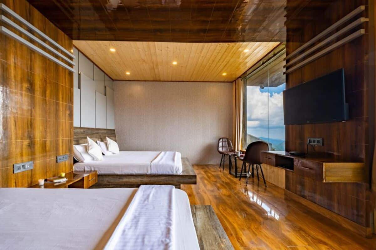 A modern hotel room with two beds, a wooden ceiling, a large window, and a flat-screen TV.