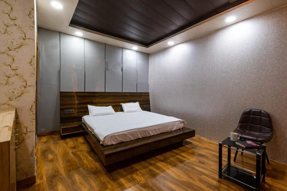 A modern bedroom with a wooden bed, built-in wardrobe, and a small table with a chair.
