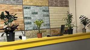 Ein Empfangstresen mit gelb-grauem Farbdesign, flankiert von einer Wand mit Ziegeloptik.