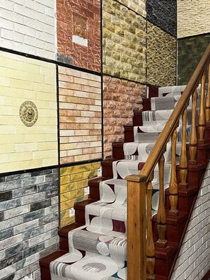 A staircase with a wooden handrail and steps covered in patterned cushions. - Edem Bishkek  (Bishkek)