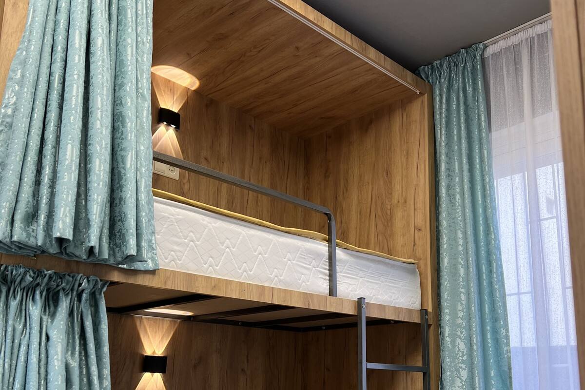 A bunk bed room with wooden walls, a ladder, and a wall-mounted light fixture.