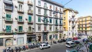 A street view with a row of parked scooters, a white car, and a yellow building labeled "Hotel Eden". - Central Station Family Apt by Wonderful Italy (Naples)