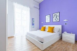 A modern bedroom with a bed, bedside tables, and artwork on the wall.
