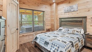 A wooden cabin bedroom with a bed, a ceiling fan, and a window with blinds. - Luxury 2 Bedroom Cabin with Hot Tub, Pool Table, Resort Amenities and More! (Sevierville)