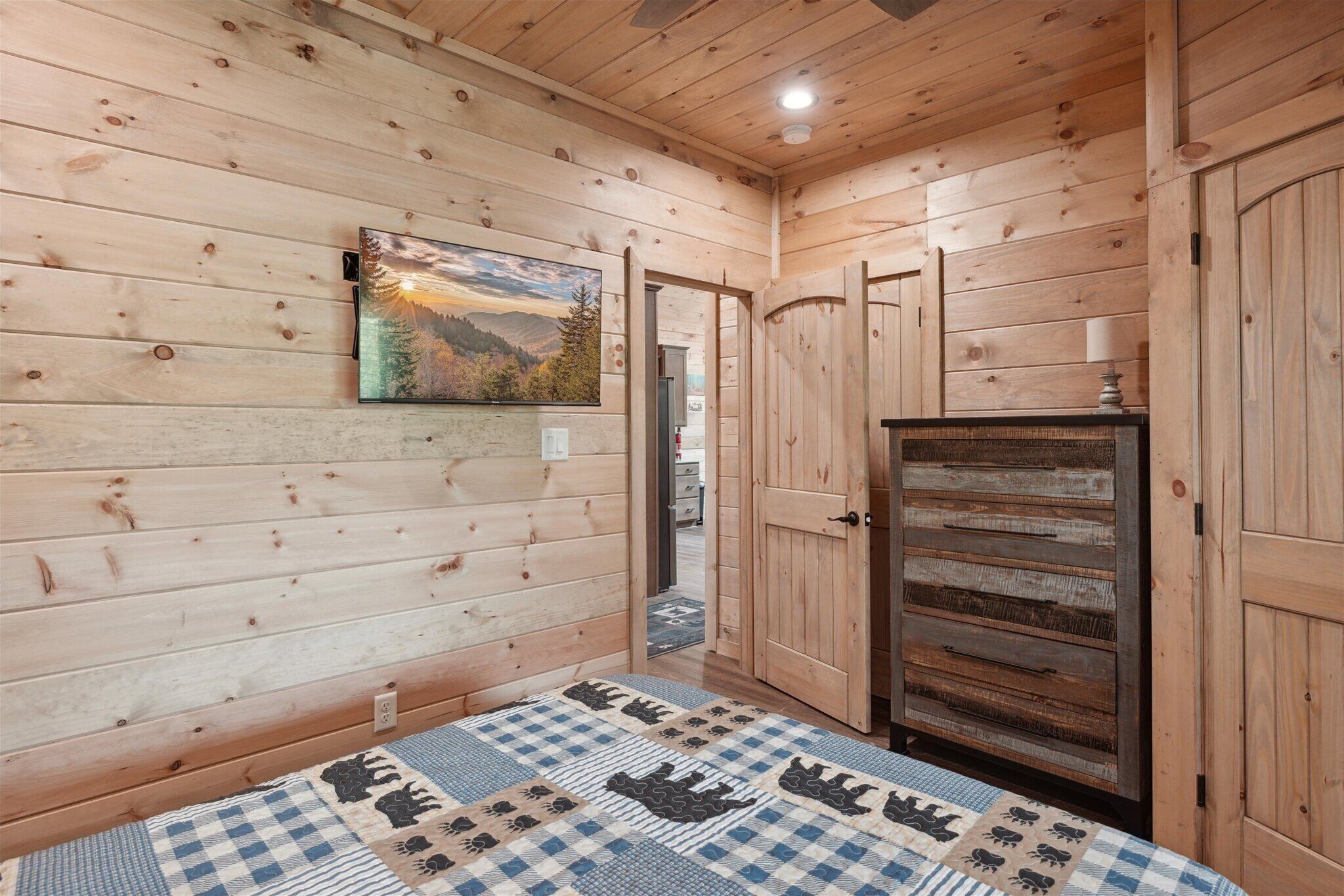 Ein Holzblockhaus-Innenraum mit einem Bett, einem Gemälde und einem Holzschrank.