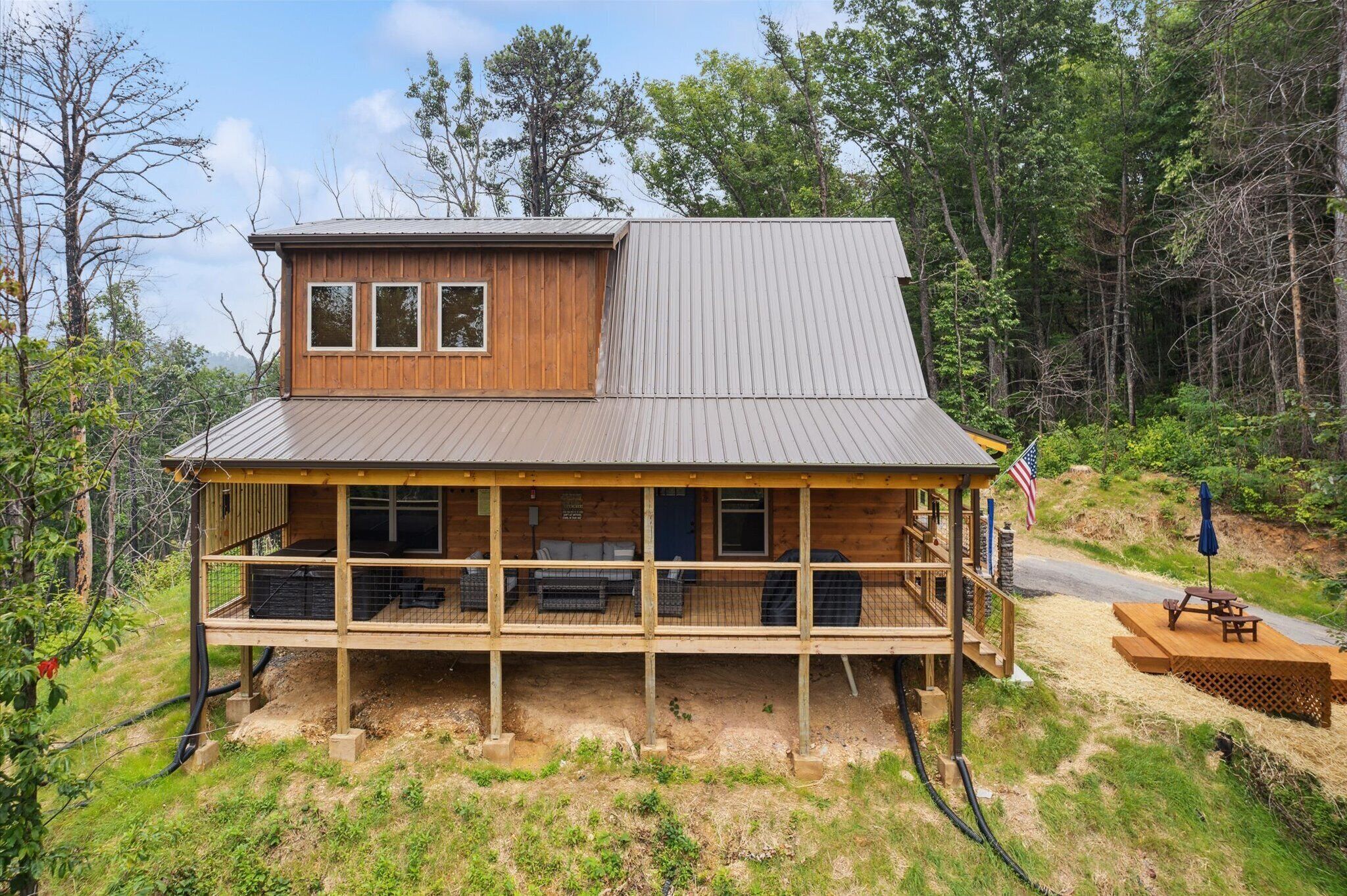 A wooden cabin with a porch, a deck, and a small outdoor seating area.