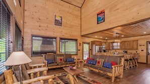 A spacious living area with a sofa set, a coffee table, and a lamp. There is a kitchen area with a dining table and chairs. - ALongViewSplash: Pool, Mtn View, Pet-Friendly, Theater, Game Room, Hot Tub, WiFi (Sevierville)