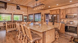 A spacious kitchen with wooden cabinetry, a large island with seating, and modern appliances. - ALongViewSplash: Pool, Mtn View, Pet-Friendly, Theater, Game Room, Hot Tub, WiFi (Sevierville)