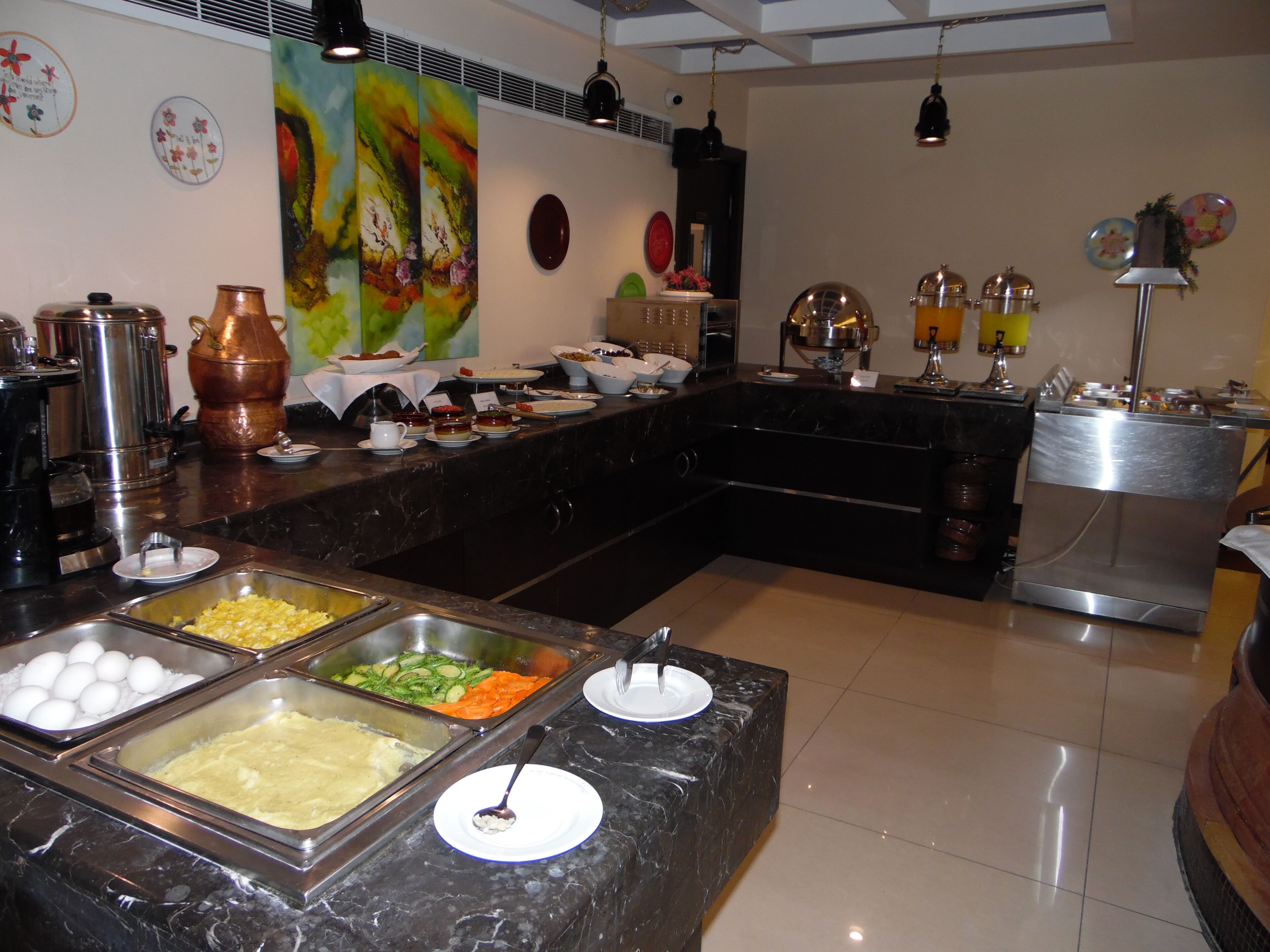 Zona de bufé con diversas opciones de comida, estación de café y pared decorativa con motivos florales.