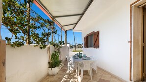 A covered patio with a table set for dining, surrounded by white walls and potted plants. - 3309 Villetta Mare Fuori - Appartamento Piccolo by Barbarhouse (Porto Cesareo)
