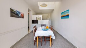 A dining area with a table set for two, a white tablecloth, and chairs. There are paintings on the walls and a ceiling light fixture. - 3310 Villetta Mare Fuori - Appartamento Grande by Barbarhouse (Porto Cesareo)