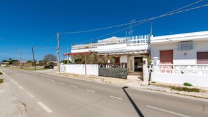 A two-story building with a white facade, a balcony, and a gated entrance. - 3310 Villetta Mare Fuori - Appartamento Grande by Barbarhouse (Porto Cesareo)
