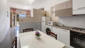 A modern kitchen with a dining area, a washing machine, a microwave, and a stove. - 3310 Villetta Mare Fuori - Appartamento Grande by Barbarhouse (Porto Cesareo)