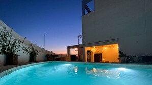 A swimming pool with a covered area and string lights, surrounded by a white building and potted plants. - STE003 Riverview 4 Bedroom House, with Private Pool (Ayamonte)