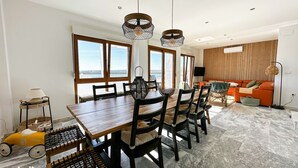 A spacious dining area with a wooden table and chairs, a large window with a view, and a modern living area with a sofa and floor lamp. - STE003 Riverview 4 Bedroom House, with Private Pool (Ayamonte)