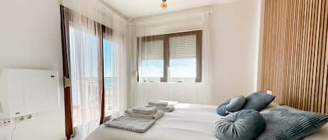 A bedroom with a bed, a window with blinds, a wooden panel wall, and a ceiling light.