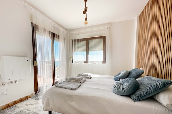 Un dormitorio con cama, una ventana con persianas, un panel de pared de madera y una lámpara de techo.