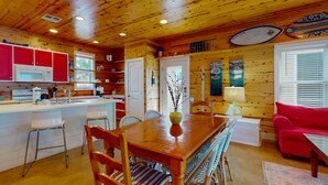 Interno di una baita in legno con cucina, zona pranzo e soggiorno.