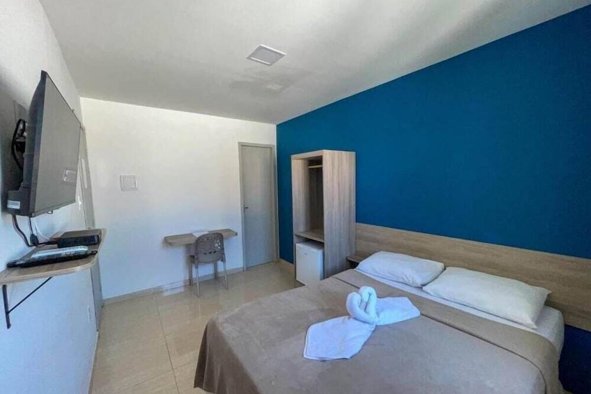 A hotel room with a bed, a TV, a desk, and a wardrobe.