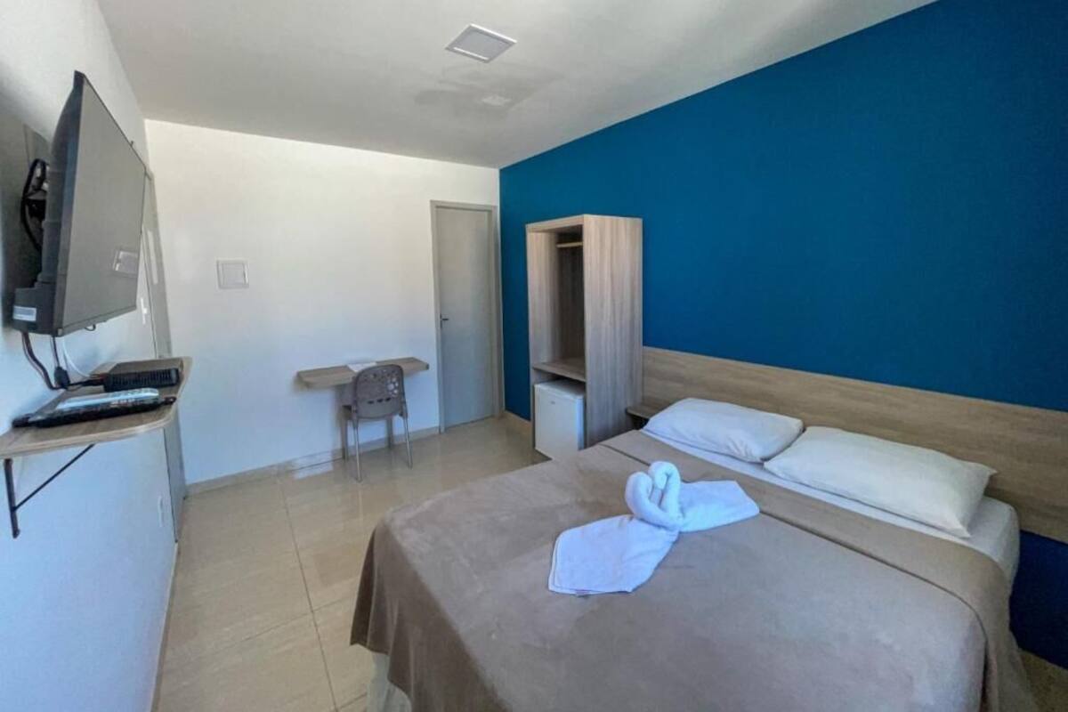 A hotel room with a bed, a television, a desk, and a wardrobe.